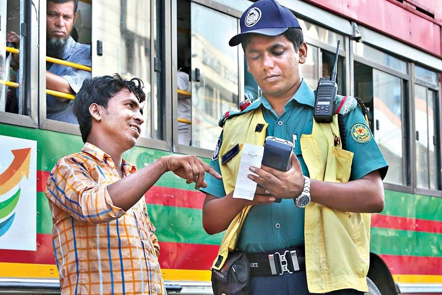 A policeman seen handing over a ticket to a vehicle driver for breaking the law. The photograph was taken at Karwan Bazar in the city — FE photo