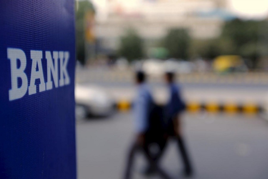 Commuters walk past a bank sign along a road in New Delhi, November 25, 2015.— Reuters/Files