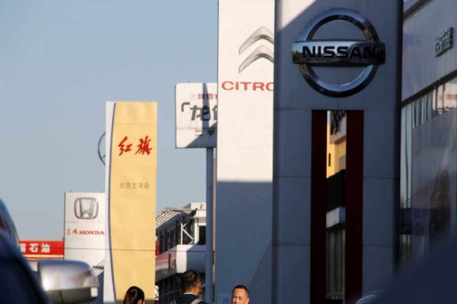 FILE PHOTO: People walk near the showrooms of Chinese and foreign car dealerships in Beijing, China, Oct. 11, 2018. REUTERS/Thomas Peter