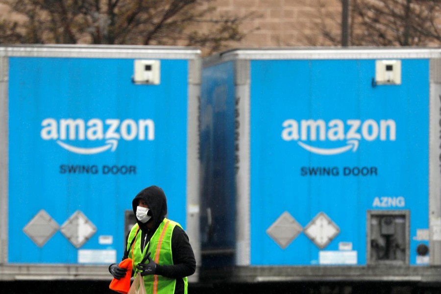 A worker in a face mask walks by trucks parked at an Amazon facility as the global coronavirus outbreak continued in Bethpage on Long Island in New York, US on March 17, 2020 — Reuters/Files