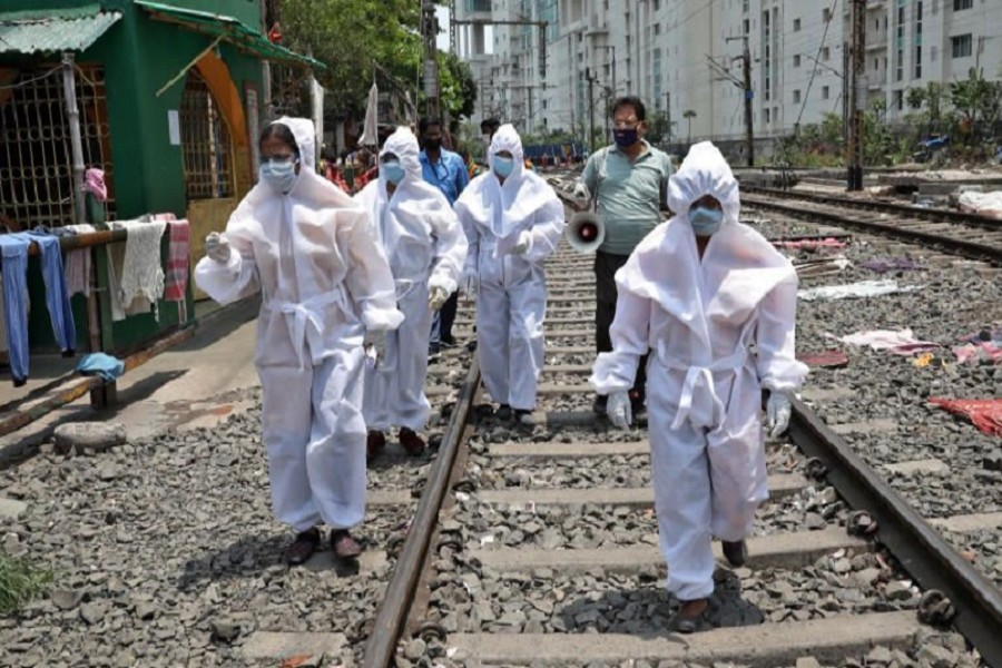 Health workers wearing protective gear walk on a railway track as they arrive in a slum area for a door-to-door verification of people to find out if they have developed any of the coronavirus disease (COVID-19) symptoms, in Kolkata, India, April 24, 2020. — Reuters