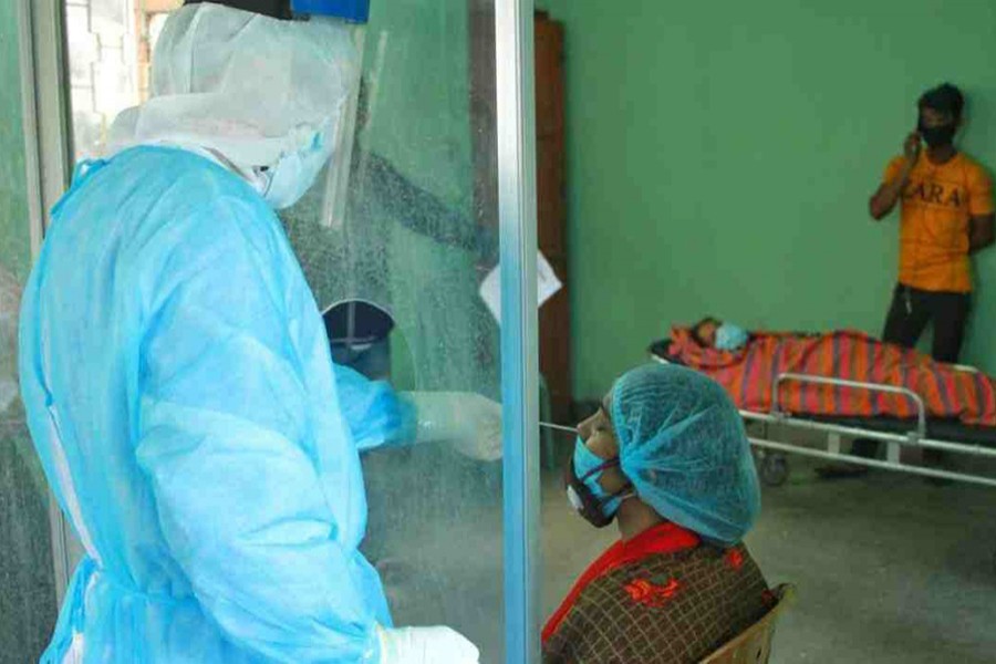 A healthcare worker in a protective chamber takes a swab sample from a woman to test for COVID-19 — UNB/Files