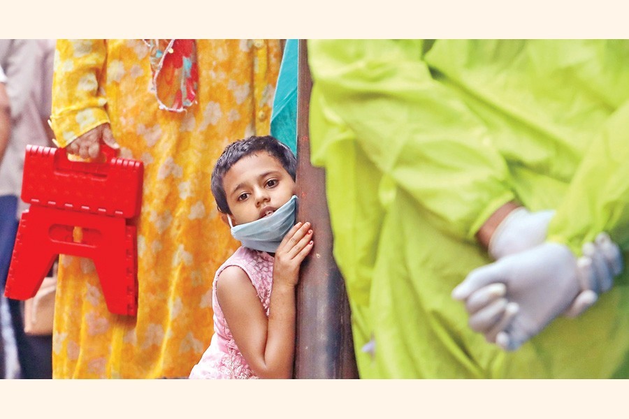 A little girl looks gloomy as she waits in a queue with her family members to take a test for coronavirus at the Sir Salimullah Medical College and Hospital in the city on Monday — FE photo by Shafiqul Alam