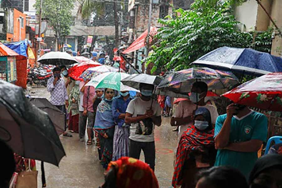 রোববার সকালে গুঁড়ি গুঁড়ি বৃষ্টির মধ্যেই রাজধানীর খিলগাঁও তিলপাপাড়ায় নগর মাতৃসদন কেন্দ্রের বাইরে ছাতা মাথায় টিকা নেওয়ার অপেক্ষায় মানুষ। ছবি: বিডিনিউজ টোয়েন্টিফোর ডটকম