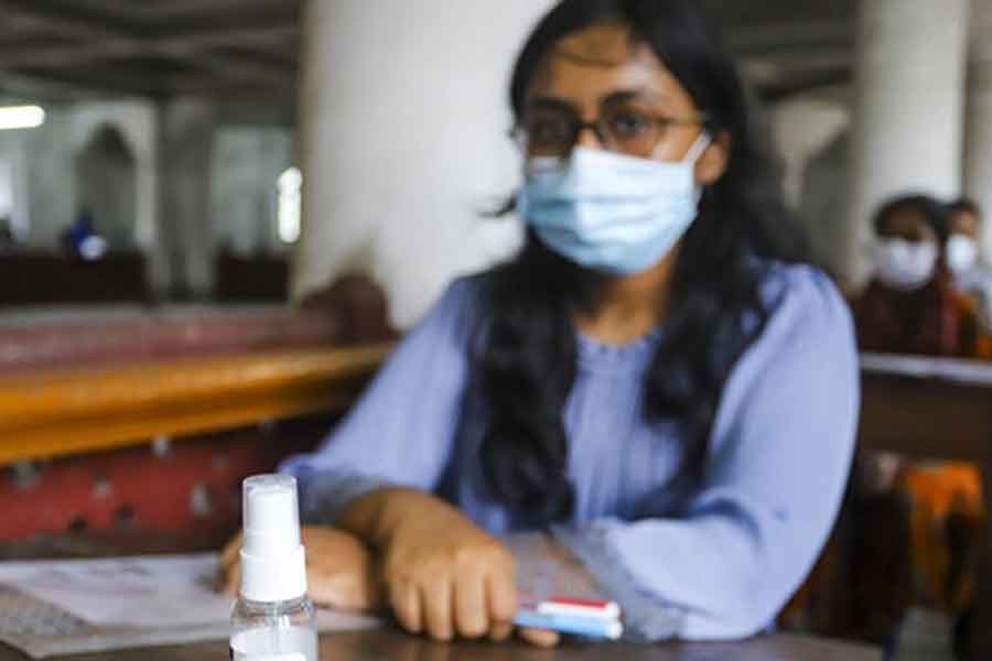 মুখে মাস্ক, পাশে হ্যান্ড স্যানিটাইজার নিয়ে কার্জন হল কেন্দ্রে ঢাকা বিশ্ববিদ্যালয়ের ভর্তি পরীক্ষায় অংশ নিচ্ছেন এক শিক্ষার্থী। ছবি: বিডিনিউজ টোয়েন্টিফোর ডটকম