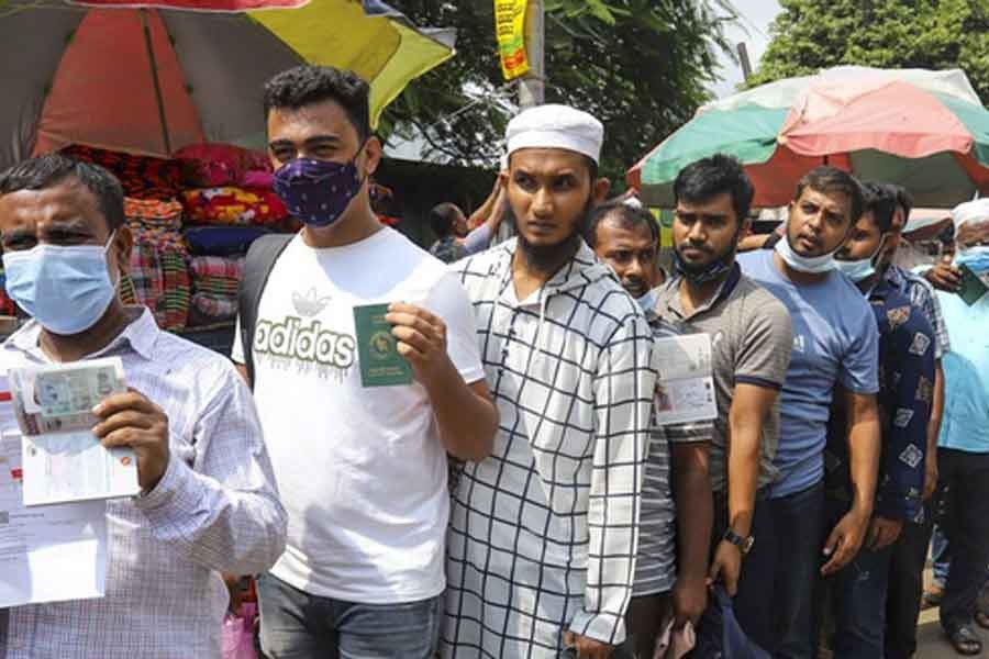 ঢাকা মেডিকেল কলেজ হাসপাতালে রোববার পাসপোর্ট ও টিকা কার্ড হাতে লাইন দাঁড়িয়ে প্রবাসীরা। করোনাভাইরাসের টিকা নিতে এসেছেন তারা। ছবি: বিডিনিউজ টোয়েন্টিফোর ডটকম