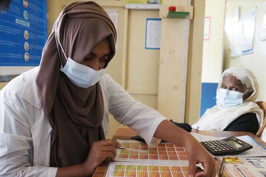 A health care worker checking the status of a patient at a medical centre in Bangladesh. —WHO Photo