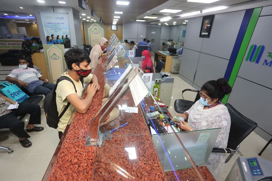 A teller is counting notes of taka at a bank counter in Dhaka. 	—FE Photo