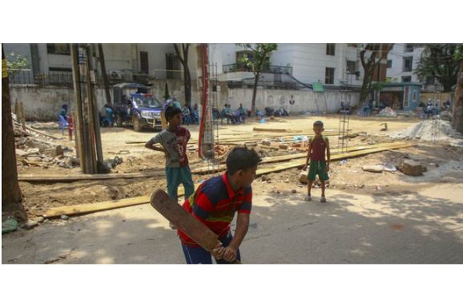 কলাবাগানের তেঁতুল তলা মাঠে থানার ভবন নির্মাণের কাজ করছেন শ্রমিকরা। পাশেই সড়কে খেলছে শিশুরা। ছবি: মাহমুদ জামান অভি/ বিডিনিউজ টোয়েন্টিফোর ডটকম