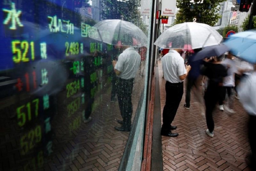 A man stands next to an electronic board showing stock prices in Tokyo, Japan, August 18, 2016. Reuters