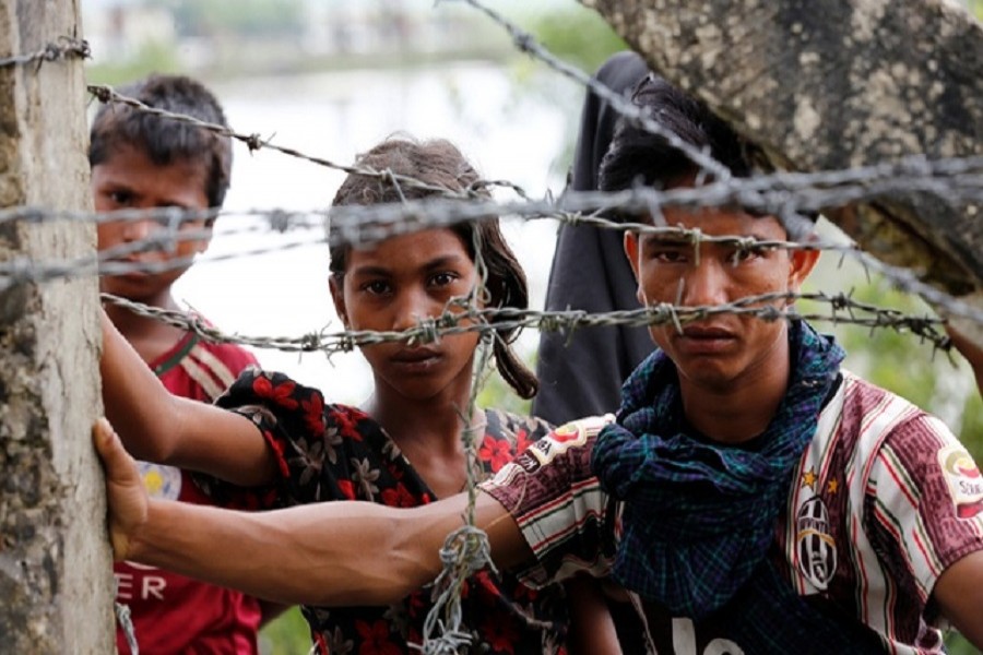 Rohingya refugees look on through barbed wire as they wait for boat to cross the border through Naf river in Maungdaw, Myanmar, Sept 7, 2017. Reuters