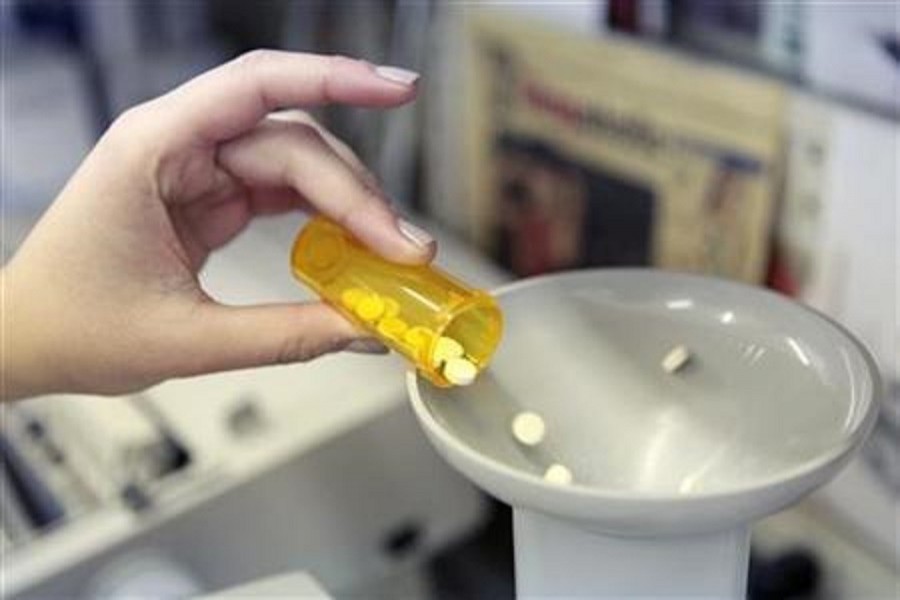 A pharmacy employee dumps pills into a pill counting machine as she fills a prescription while working at a pharmacy in New York December 23, 2009. Reuters