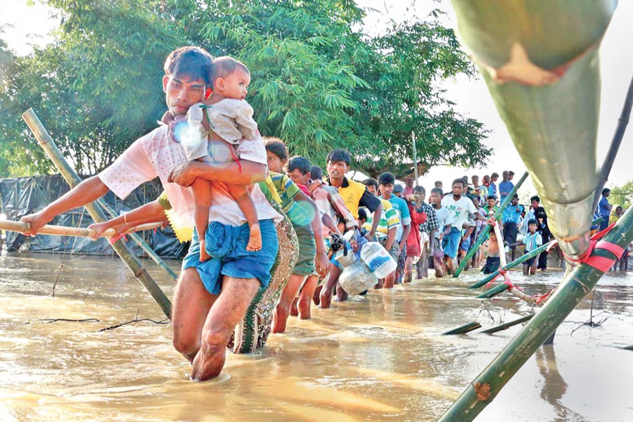 A group of Rohingya people from Ghumdhum refugee camp at Ukhia in Cox's Bazar move to safer places after downpour inundates their makeshift refuge on Sunday. 	— Focus Bangla