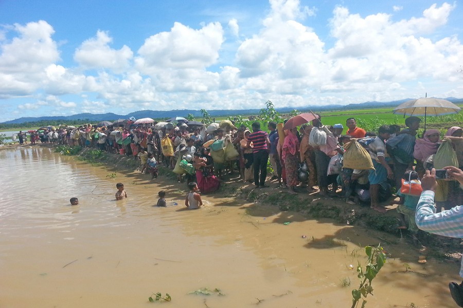 A group of Rohingyas walking towards a refugee camp after crossing the Bangladesh-Myanmar border through Ukhia in Cox’s Bazar on Sunday.	— FE photo