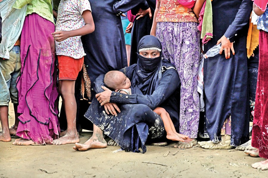 A group of Rohingya refugees wait to receive aid in Cox's Bazar on Wednesday. 	—  Reuters