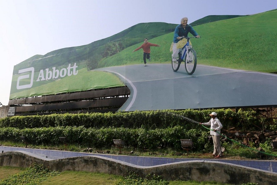 A worker waters plants next to an advertisement billboard of Abbott in Mumbai, India, November 12, 2015. Reuters/File photo