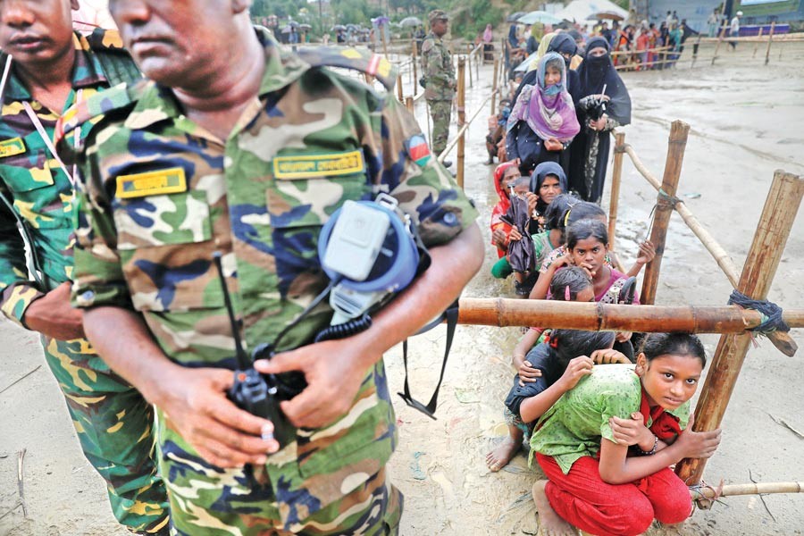 Rohingya refugees who earlier fled from Myanmar and took shelter at a camp in Cox's Bazar wait for aid on Sunday. 	— Reuters