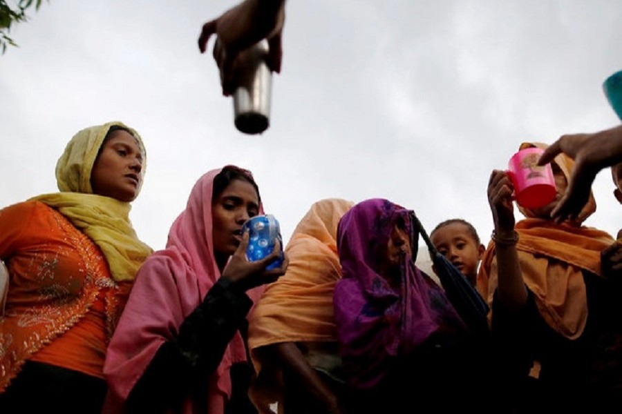 Local Bangladeshi people offer water as Rohingya refugees arrive in Teknaf, Bangladesh, September 1, 2017. Reuters