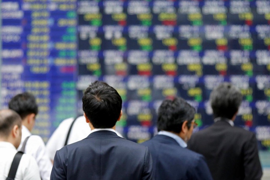 People walk past an electronic stock quotation board outside a brokerage in Tokyo, Japan, September 22, 2017. Reuters