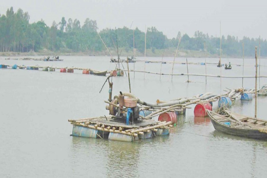 Some influential people are lifting sand from the Atrai river under Manda upazila in Naogaon defying an official ban. The snap was taken on Wednesday.  	— FE Photo