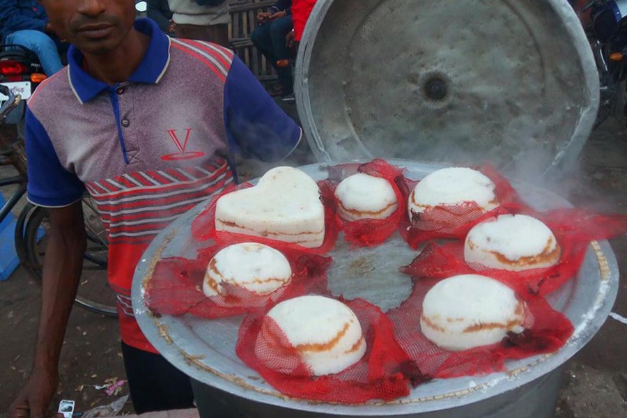 Bhapa Pitha, a piping hot cake, is on display for sale at a roadside makeshift shop at the railway station under Sadar upazila in Bogra. Photo taken Sunday night. FE Photo