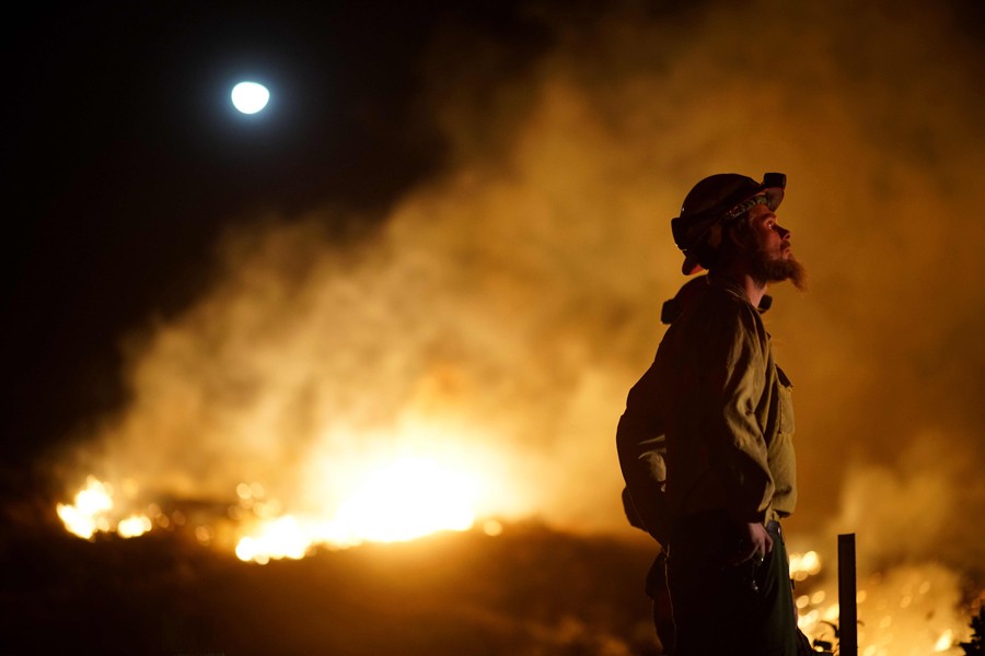 LOS ANGELES: A firefighter watches the fire line at the Lilac fire in Bonsall, California on Thursday.	— AFP