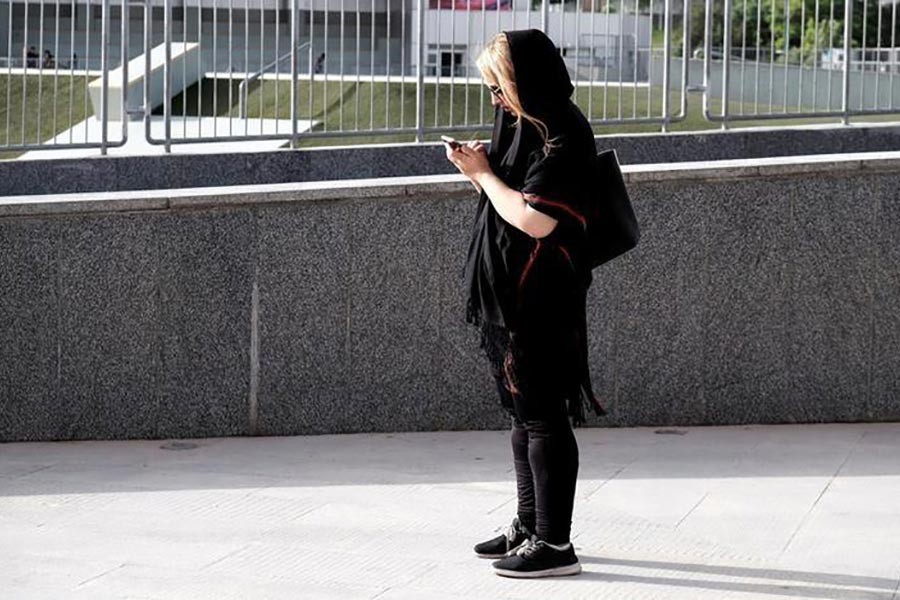 An Iranian woman uses her mobile phone at a park in Tehran, Iran. -Reuters Photo