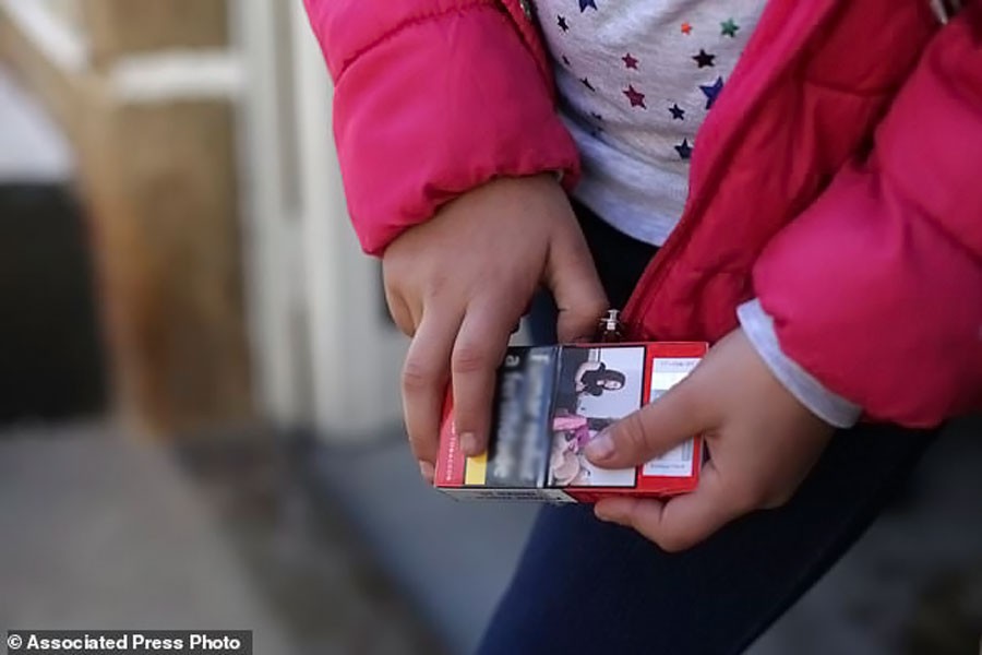 Natasha, 8 years old, holds a packet of cigarettes in the village of Vale de Salgueiro, northern Portugal while celebrating the Epiphany festival (AP photo)