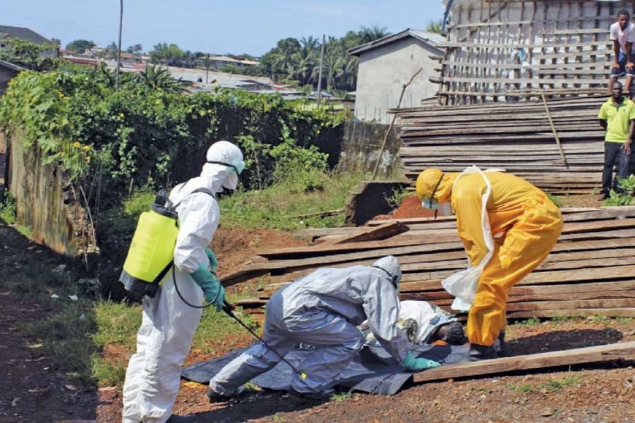 Health workers remove the body a woman who died from the Ebola virus in the Aberdeen district of Freetown, Sierra Leone, on October 14, 2014.	 —Photo: Reuters