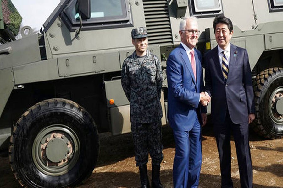 Australian PM Malcolm Turnbull, center, and Japanese counterpart Shinzo Abe, right, shake hands in front of a Bushmaster Protected Mobility Vehicle in Funabashi, east of Tokyo, Jan 18, 2018. AP