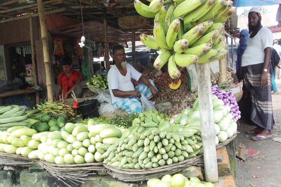 A vegetable seller waits for customers at his shop in a kitchen market of Bogra on Monday. 	— FE Photo