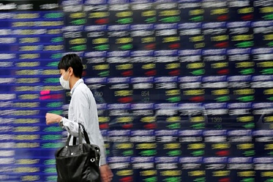 People walk past an electronic stock quotation board outside a brokerage in Tokyo, Japan, September 22, 2017. Reuters/File Photo