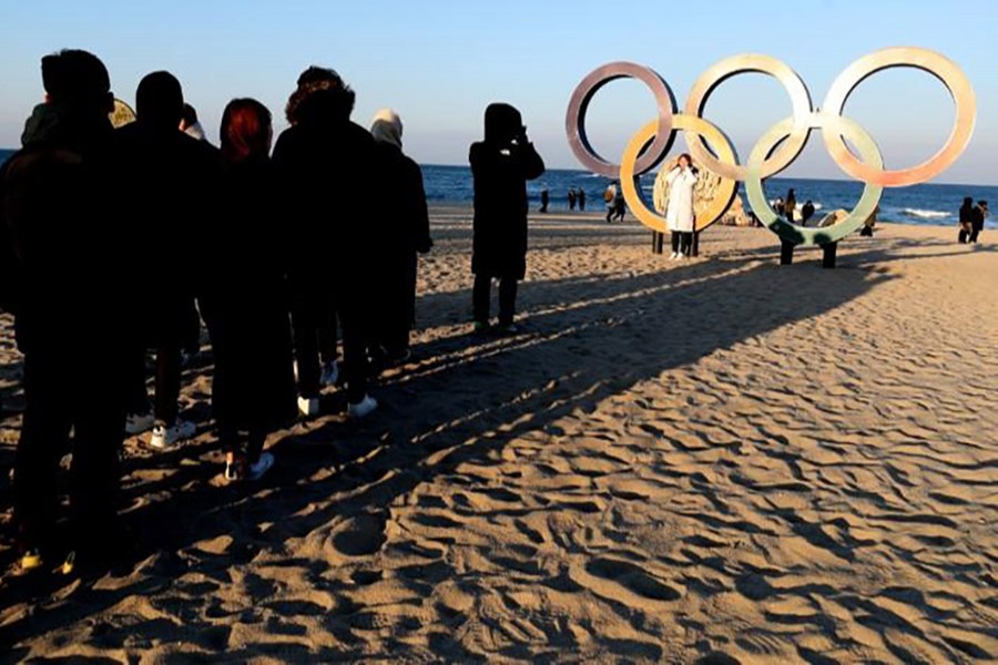 People form a line and wait their turn to take pictures with the Olympic Rings on Gyeongpo Beach by the Sea of Japan in Gangneung-si, South Korea on Saturday. - Reuters