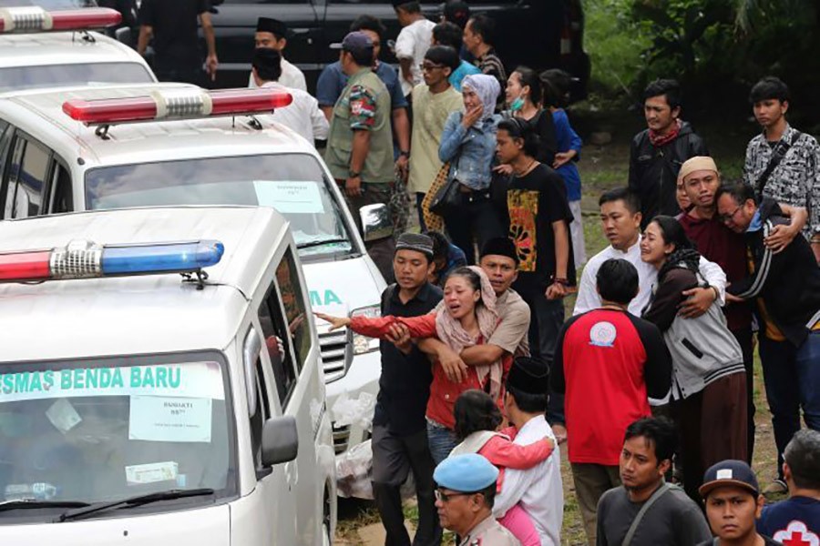 Relatives react as ambulances carrying the bodies of the victims of the bus accident arrive at their home village in East Ciputat, Indonesia on Sunday. - AP photo