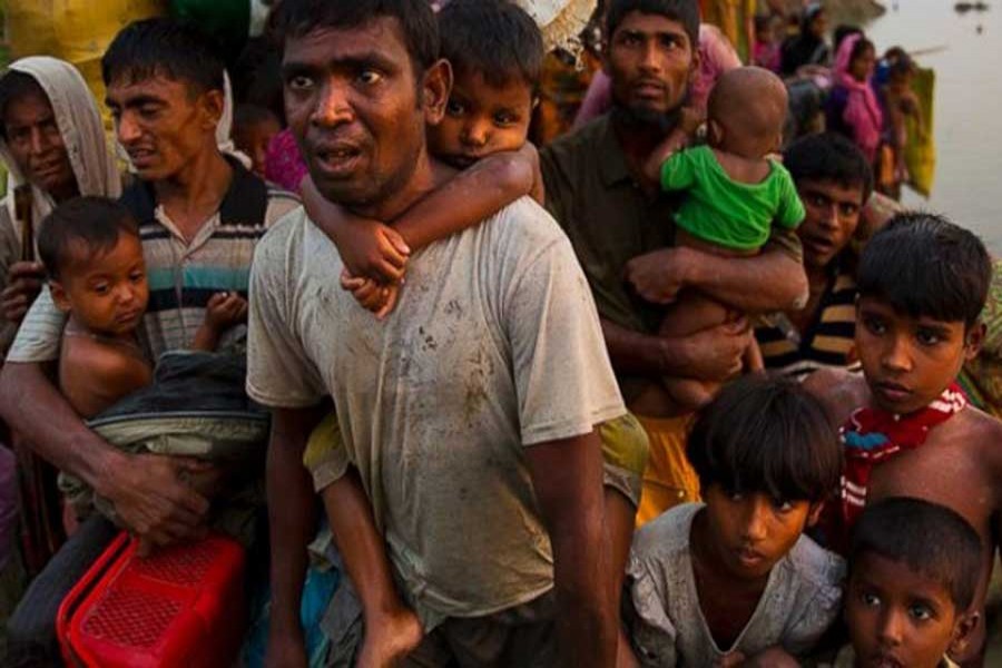 In this November 1, 2017, file photo, Rohingyas carry their young children and belongings after crossing the border from Myanmar into Bangladesh, near Palong Khali, Bangladesh. AP