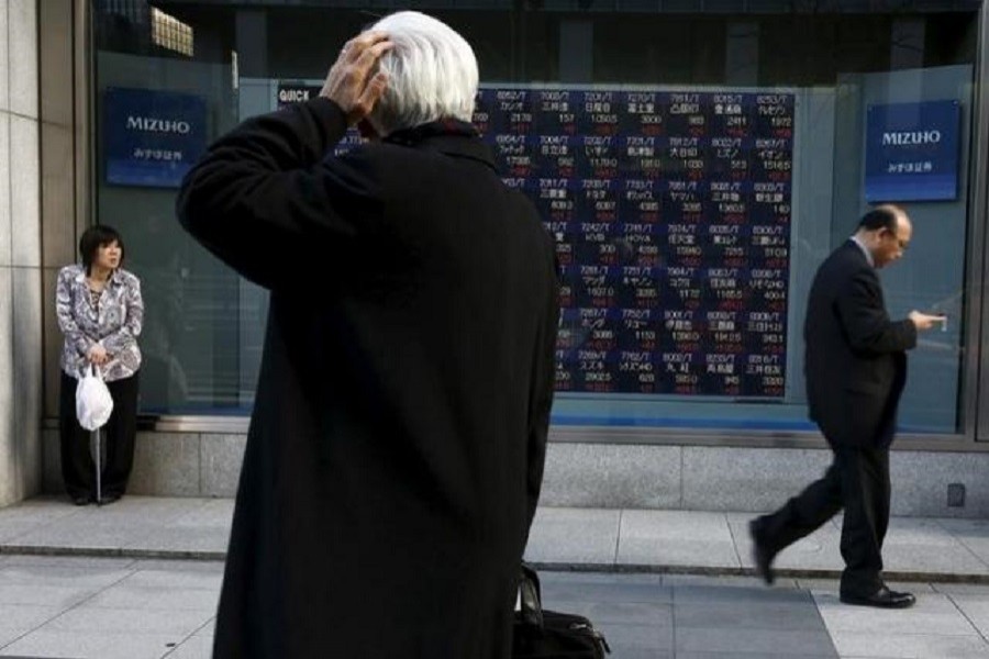 A man looks at an electronic board showing market indices outside a brokerage in Tokyo, Japan, March 2, 2016. Reuters