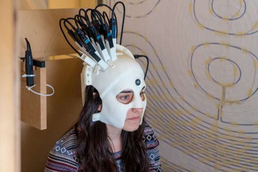 A woman demonstrates use of the brain scanner. Image Credit: Wellcome/Nature