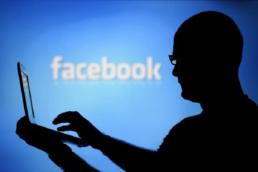 A man is silhouetted against a video screen with a Twitter and a Facebook logo as he poses with a laptop in this photo illustration taken in the central Bosnian town of Zenica, August 14, 2013. Reuters/Files