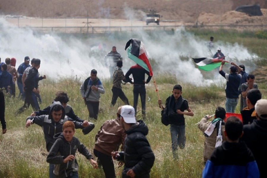 Palestinians run from tear gas fired by Israeli troops during clashes, during a tent city protest along the Israel border with Gaza, demanding the right to return to their homeland, east of Gaza City Mar 30, 2018. Reuters