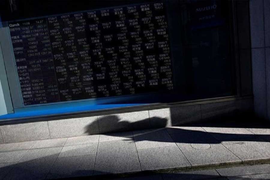 A pedestrian casts a shadow in front of an electronic stock quotation board outside a brokerage in Tokyo, Japan, November 9, 2016. Reuters