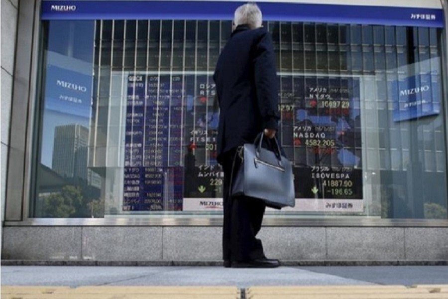 A pedestrian stands to look at an electronic board showing the stock market indices of various countries outside a brokerage in Tokyo, Japan, February 26, 2016. Reuters/Files