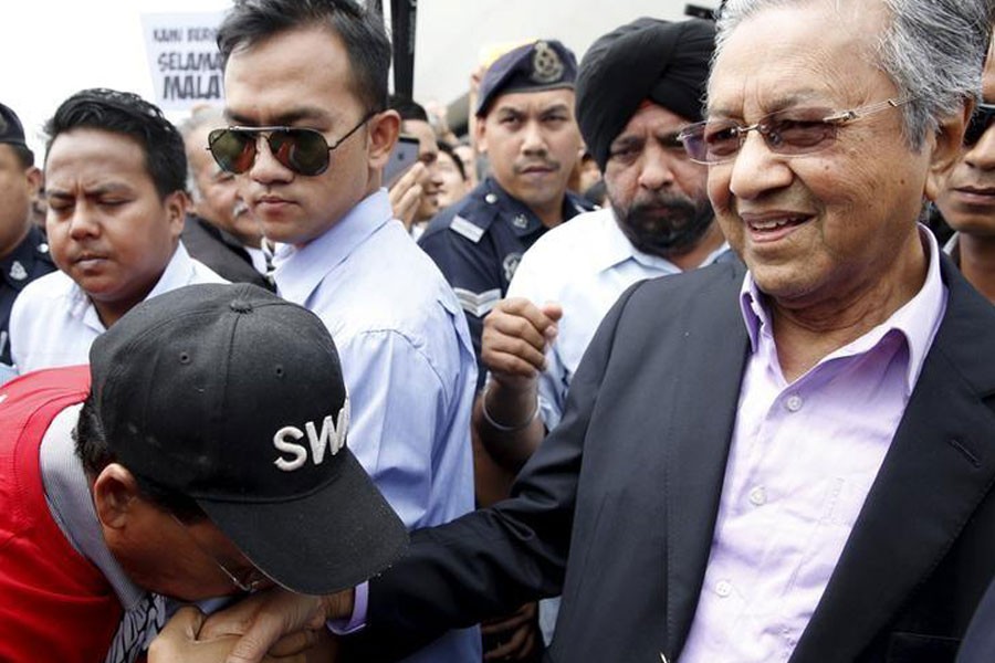 A supporter kisses the hand of former Malaysian Prime Minister Mahathir Mohamad as he arrives at Subang airport, outside Kuala Lumpur, Malaysia, September 9, 2015. Reuters.