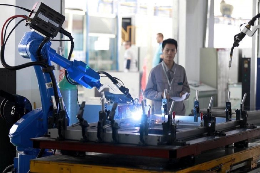 A worker monitors a robotic arm working inside a factory in Huaian, Jiangsu province, China May 15, 2018. Reuters/Files