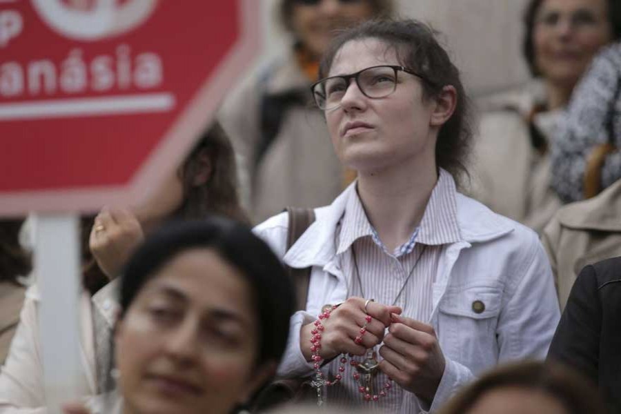 People stand on the steps of the Portuguese parliament in Lisbon on Thursday during a protest against euthanasia. - AP