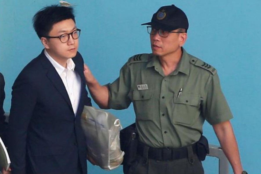 Pro-independence activist Edward Leung is held by a correctional services department officer inside a detention centre before leaving for the High Court for a sentencing hearing in Hong Kong, China June 11, 2018. Reuters.