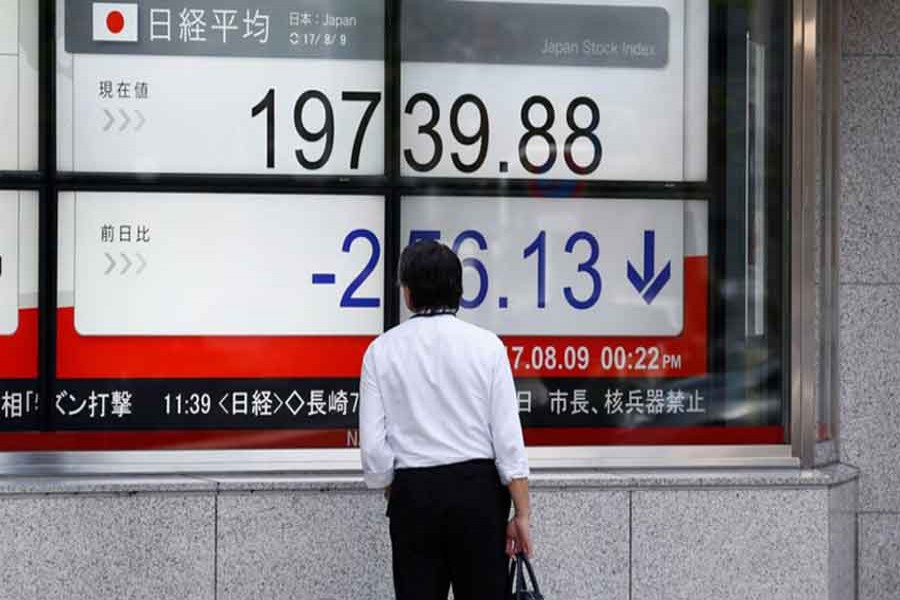 A man looks at an electronic board showing Japan's Nikkei average outside a brokerage at a business district in Tokyo, Japan, August 9, 2017. Reuters/Files