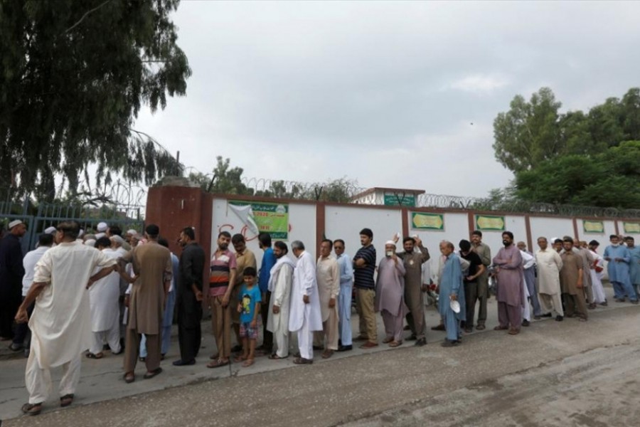 People stand in a line as they wait for a polling station to open, during general election in Rawalpindi, Pakistan on Wednesday — Reuters