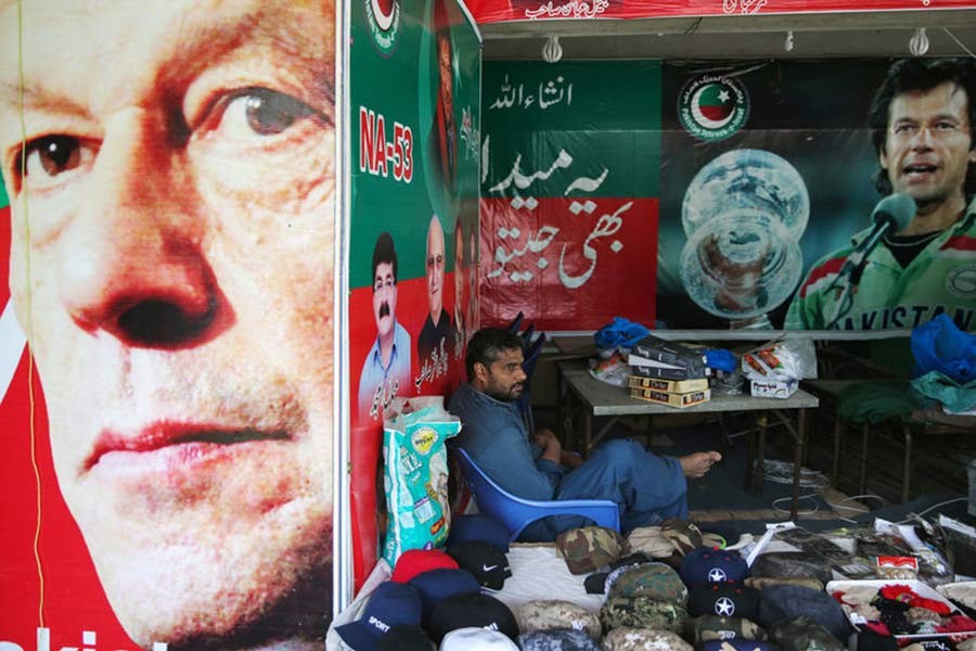 A vendor sitting next to images of cricket star-turned-politician Imran Khan, chairman of Pakistan Tehreek-e-Insaf (PTI) at a market in Islamabad of Pakistan on Friday. -Reuters Photo