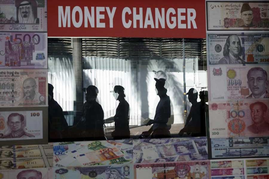 Pedestrians are reflected in a money changer's screen in Kuala Lumpur, Malaysia, August 21, 2015. Reuters/File Photo