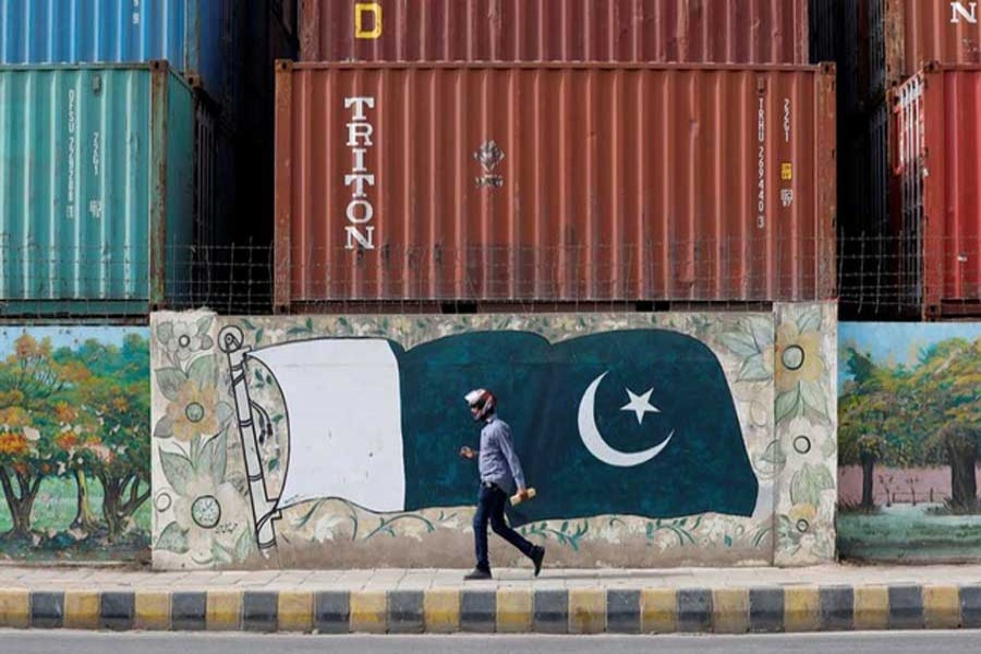 A man walks past a wall of a shipping container's yard painted with a national flag ahead of Pakistan's Independence Day, in Karachi, Pakistan Aug 6, 2018. Reuters